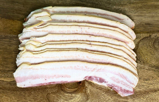 Thick-cut slices of cured and smoked heritage pork bacon from The MF Farmstead in Carrollton, Georgia, showing rich marbling and golden edges.