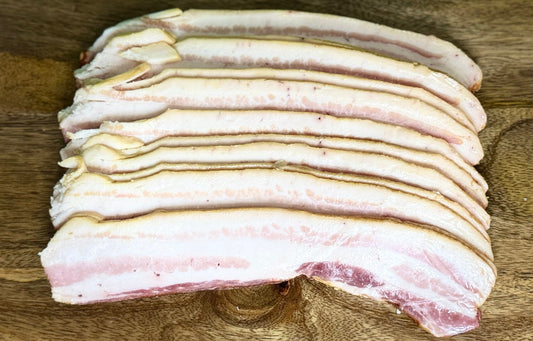 Thick-cut slices of cured and smoked heritage pork bacon from The MF Farmstead in Carrollton, Georgia, showing rich marbling and golden edges.