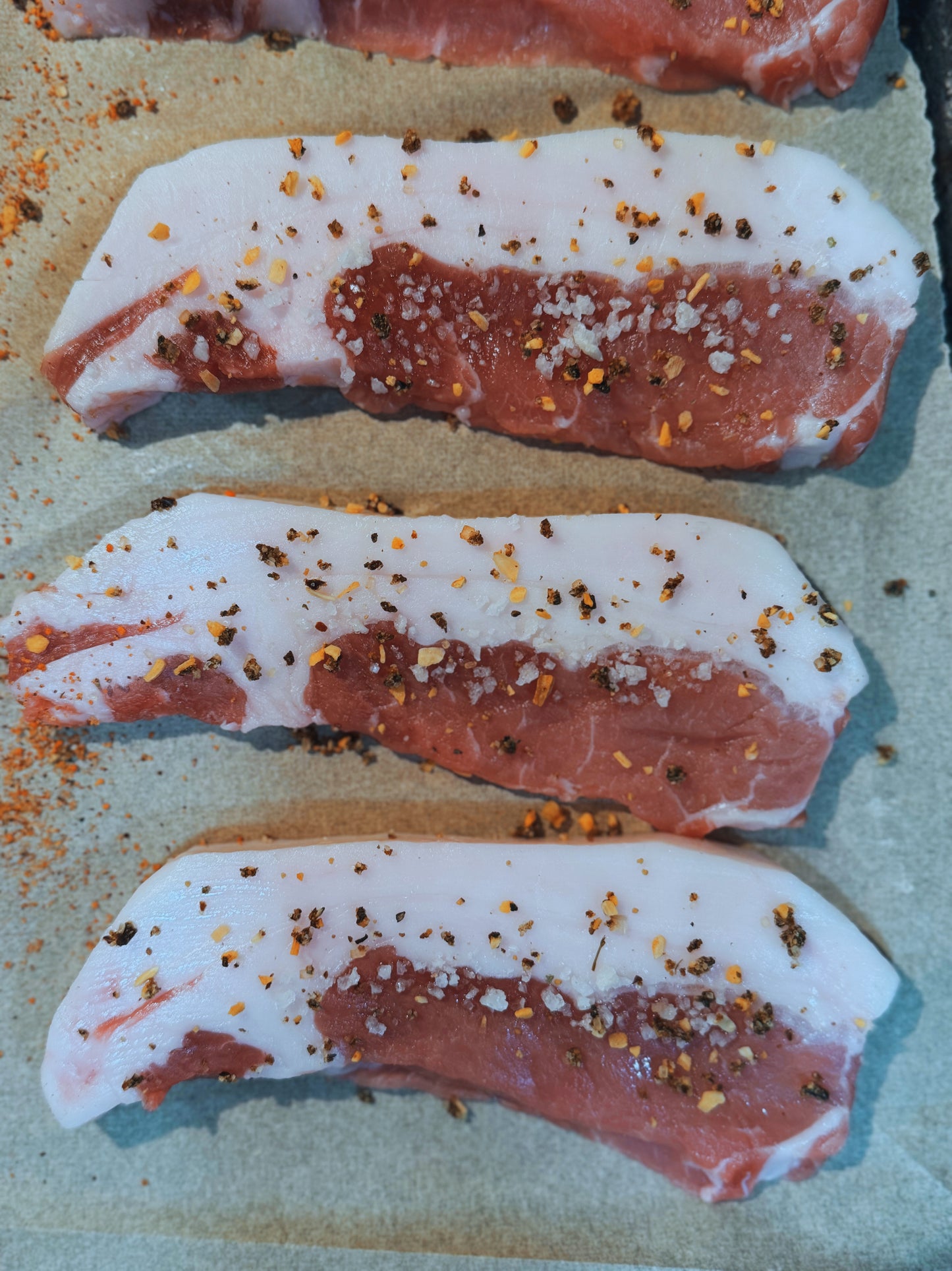 Seasoned Meishan heritage pork chops from The MF Farmstead in Carrollton, Georgia, pasture-raised and prepared with coarse salt and crushed pepper.