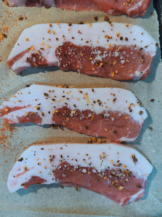 Seasoned Meishan heritage pork chops from The MF Farmstead in Carrollton, Georgia, pasture-raised and prepared with coarse salt and crushed pepper.